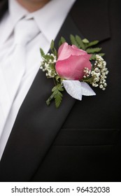 Pink rose boutonniere flower on groom's wedding coat