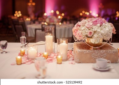 Pink rose petals ligh between white candles standing on the dinner table
