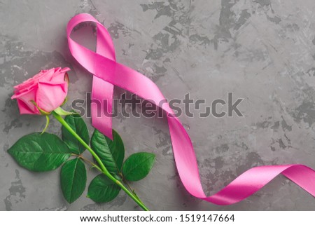 pink rose and ribbon on concrete background. Breast Cancer Awareness Month concept, copy space