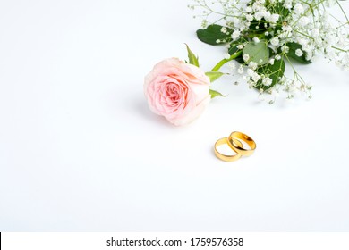  pink rose and wedding rings over white background
