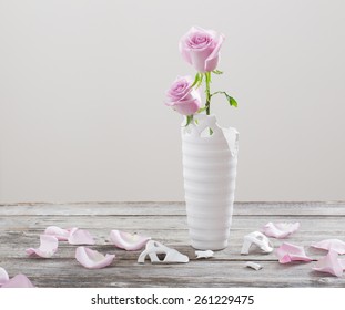 pink roses in  broken  flower vase on old wooden table