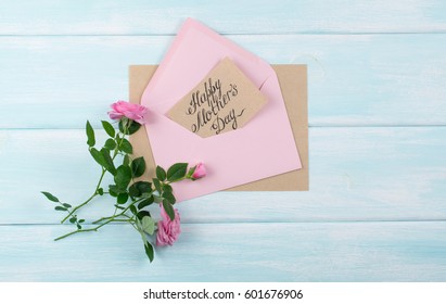 Pink Roses With Paper Greeting Card For Mothers Day In Envelope On Background Of Shabby Wooden Planks. Top View. Flat Design. Copy Space.