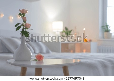 pink roses in vase on table in bedroom