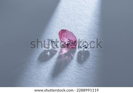Pink round cut diamond in the process of evaluation on light background.