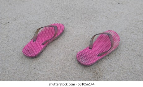 pink rubber flip flops on sand. Concept of summer tropical vacation holiday. Copy space.


