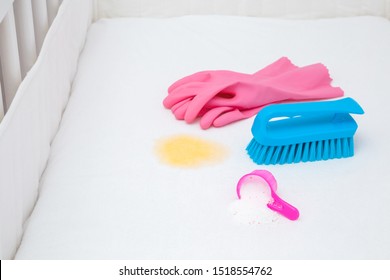 Pink Rubber Protective Gloves, Scoop Of Washing Powder And Brush In Baby Crib. Fresh Urine Stain Removing From White Mattress.