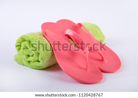 Pink sandal flip flop on green towel and white background. Summer vacations concept, close up