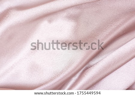 Pink satin fabric. Textile background. Powdery color. Waves and folds of fabric.