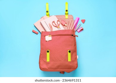 Pink school bag with stationery on blue background - Powered by Shutterstock