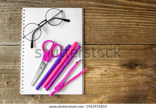 Pink scissors, notepad and markers.\
The concept of school, creativity, childhood and\
work.