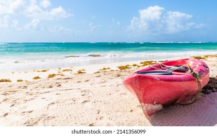 Pink Sea Kayak Parked On A Beach On A Hot Sunny Day Next To A Turquoise Blue Sea In An Exotic Travel Destination.