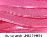 Pink shimmering lip gloss texture background. Smudged cosmetic product smear. Makup swatch product sample