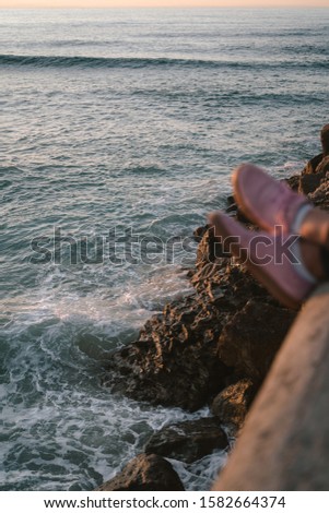 Pink shoes hanging off a ledge above the sea