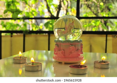 A Pink Snow Globe With Four Purple Candles And Tree Leaves