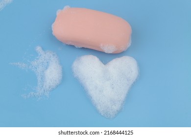 Pink soap bar and heart shaped foam bubbles on blue background. Softness and love concept. - Powered by Shutterstock