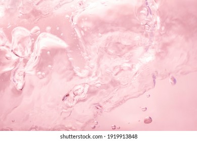 Pink splashing cosmetic moisturizer, micellar water,  toner, or emulsion abstract background. Transpatent texture with bubbles