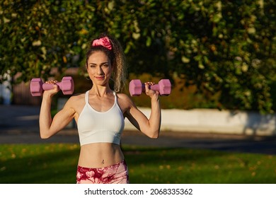 Pink Sports Outfit With Pink Dumbells And Attractive Athletic Woman.