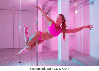 Pink sportswear. Professional experienced pole dancer with long wavy hair wearing pink sportswear - Powered by Shutterstock