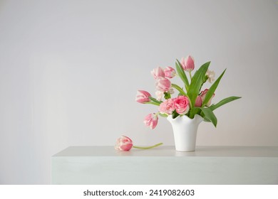 pink spring flowers in white ceramic vase in modern home interior