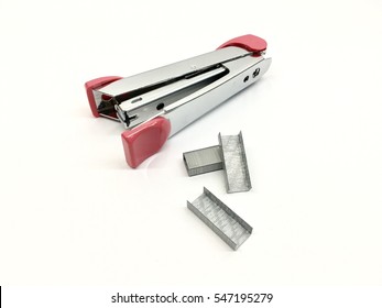Pink stapler and piles of copper office staples on white background, closeup, top view