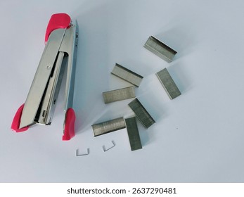 

A pink stapler and its staples on white paper.