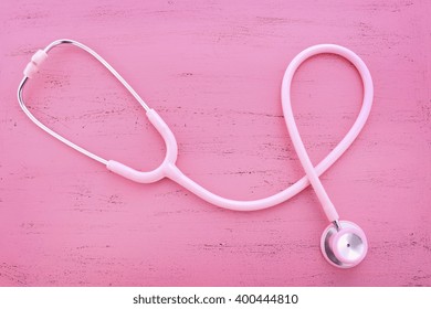 Pink Stethoscope on pink wood table for womens health awareness. 