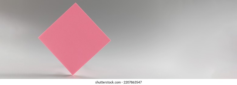 Pink Sticker Standing On Sharp Edge On Grey Background