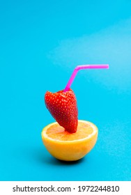 Pink Straw In Fresh Strawberry Filled With Juice On Slice Of Orange Against Sky Blue Cyan Background. Minimal Summer Fruit Composition. Food Art.