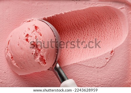pink strawberry ice cream ball in a spoon, top view