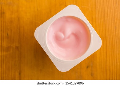 Pink Strawberry Yogurt In Small Plastic Cup Isolated On Wooden Table - Top View Photo