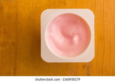 Pink Strawberry Yogurt In Small Plastic Cup Isolated On Wooden Table - Top View Photo