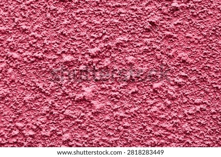 A pink stucco surface featuring a bold, roughcast texture.