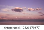Pink Sunset Clouds Floating Above Calm Lake and Distant Forest Horizon
