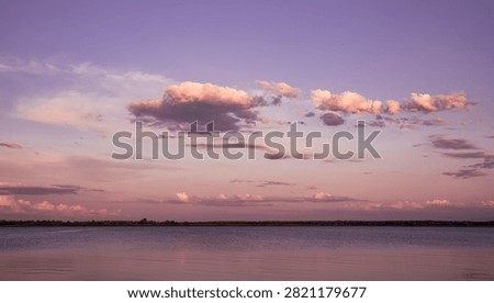 Pink Sunset Clouds Floating Above Calm Lake and Distant Forest Horizon