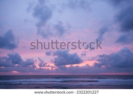 Pink sunset emerges above and across the ocean.