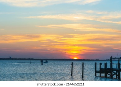 Pink sunset over the Indian River. On the horizon in the distance
  boat with fishermen returning home. The beautiful nature of Florida - Powered by Shutterstock