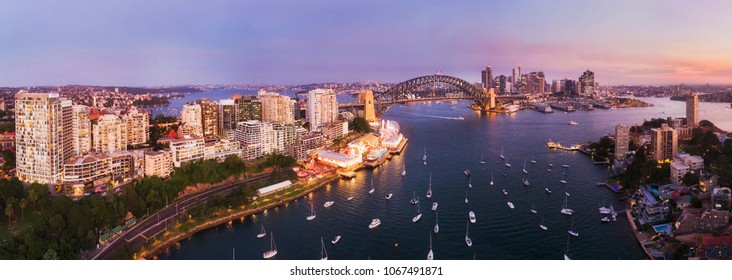 Pink sunset over Sydney city CBD landmarks around Sydney harbour connected by the Sydney harbour bridge in elevated aerial panorama from Lavender bay and North Sydney shores.