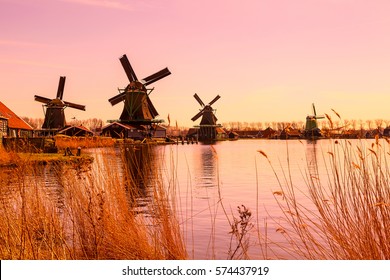 Pink sunset panoramic view of windmills in Zaanse Schans, traditional village in Holland, reflection in lake