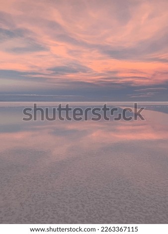 Pink sunset sky clouds and sea water.