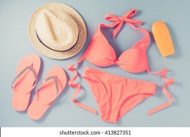 Pink swimsuit with beach accessories on blue background