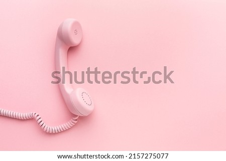 Pink telephone receiver on pink background . High quality photo