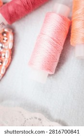 Pink thread spools and lace on white surface, sewing, threads, c