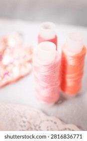 Pink thread spools and lace on white surface, sewing, threads, c