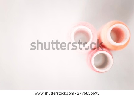 Pink thread spools and lace on white surface, sewing, threads, c