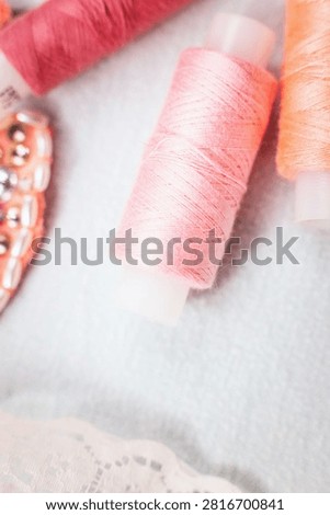 Pink thread spools and lace on white surface, sewing, threads, c