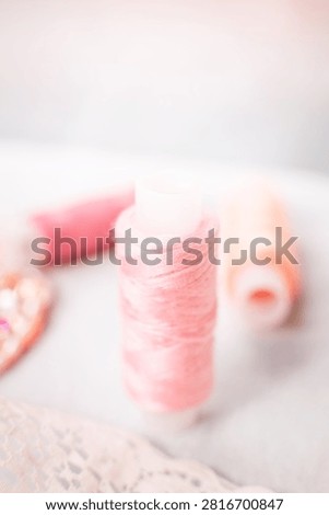 Pink thread spools and lace on white surface, sewing, threads, c