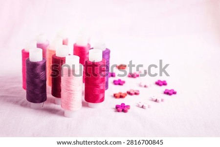 Pink thread spools scattered on white surface, sewing, threads, 