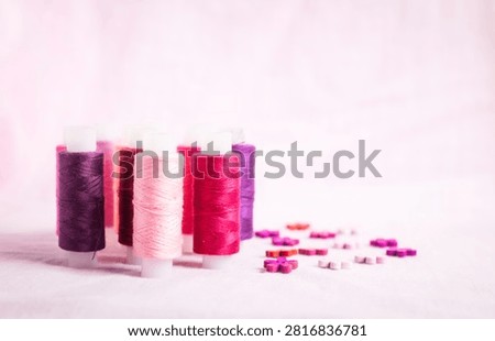 Pink thread spools scattered on white surface, sewing, threads, 