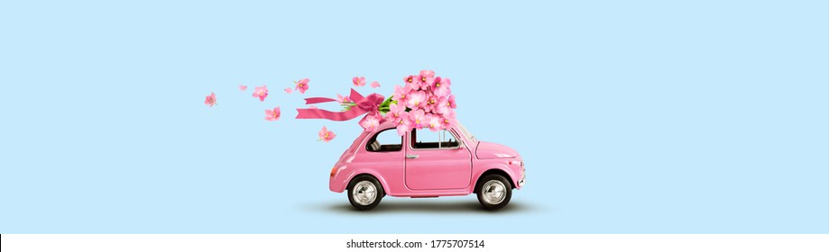 Pink Toy Car With Bouquet Of Flowers On A Roof With Ribbon And Bow On Blue Background. Flowers Delivery.