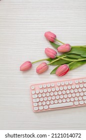 Pink tulip and computer laptop keyboard on white wood, top view, copy space. Women day celebration